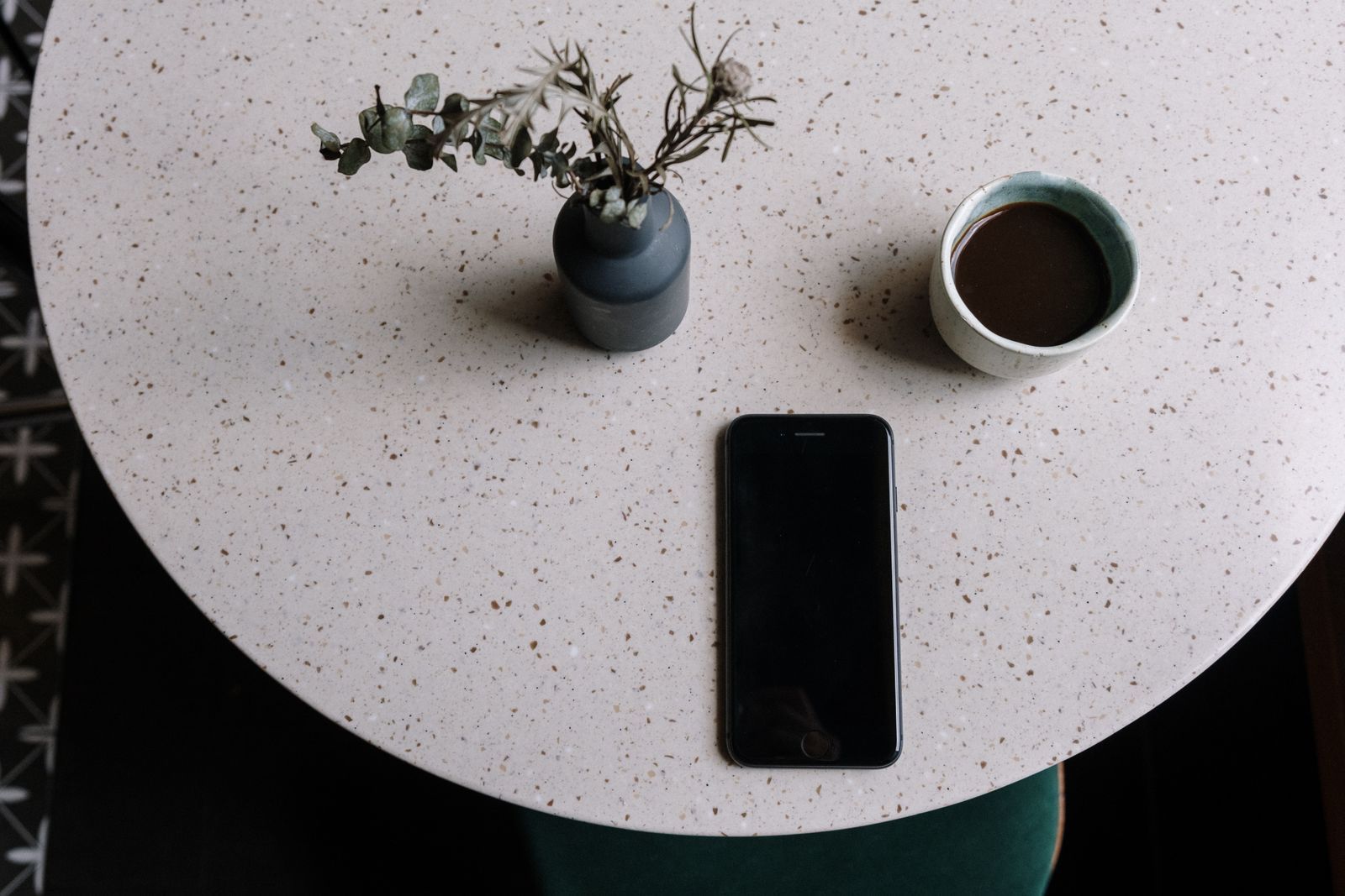 Smartphone resting on a round table beside a coffee cup in a minimalist calm setting