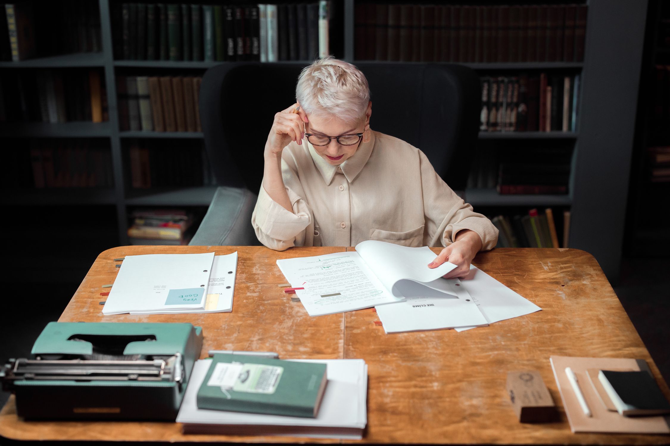 Woman over 50 reviewing papers at a wooden desk