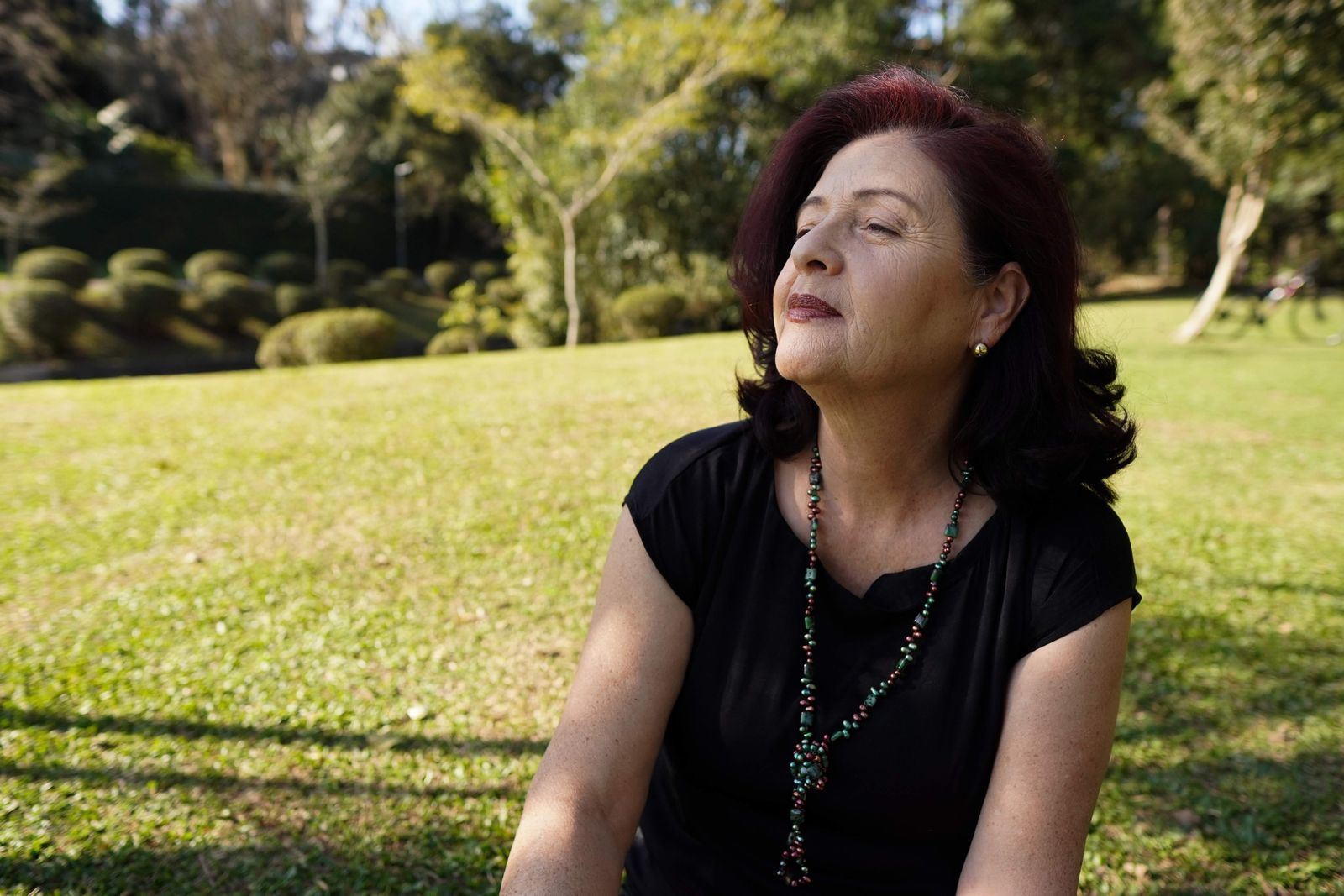 Mature woman sitting with eyes closed in a sunlit park