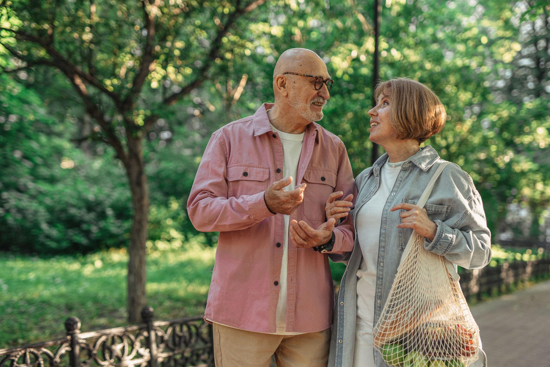 Senior couple walking together through a sunny park in conversation
