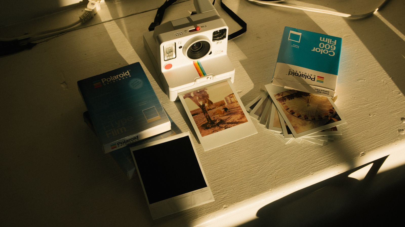 Polaroid camera with instant prints on a warm table in soft natural light