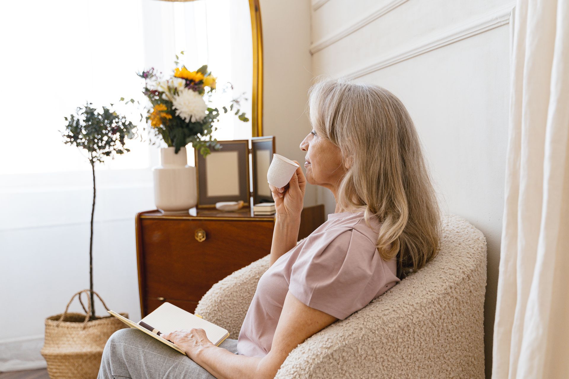 Senior woman with grey hair relaxing with a cup of tea in a quiet living room