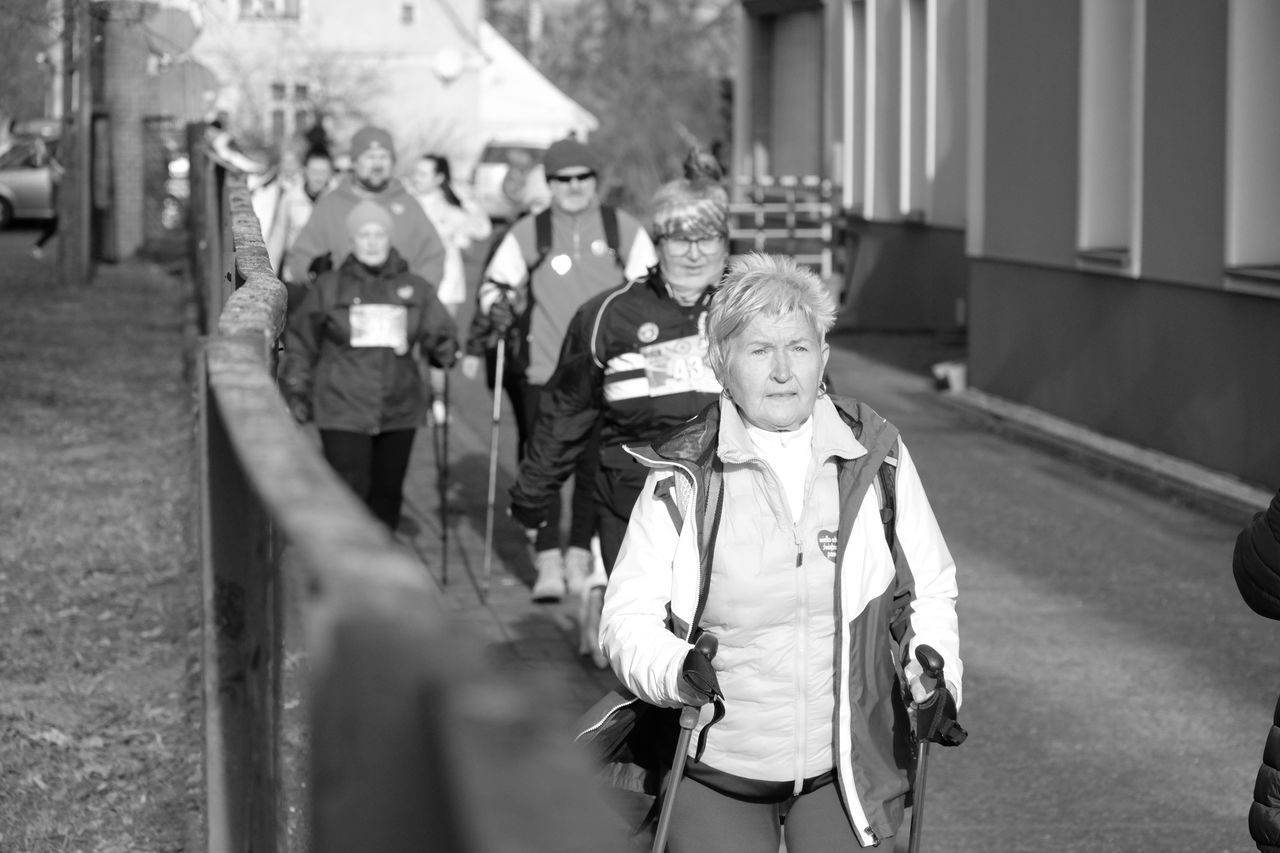Group of older adults Nordic walking together along a path in a community event