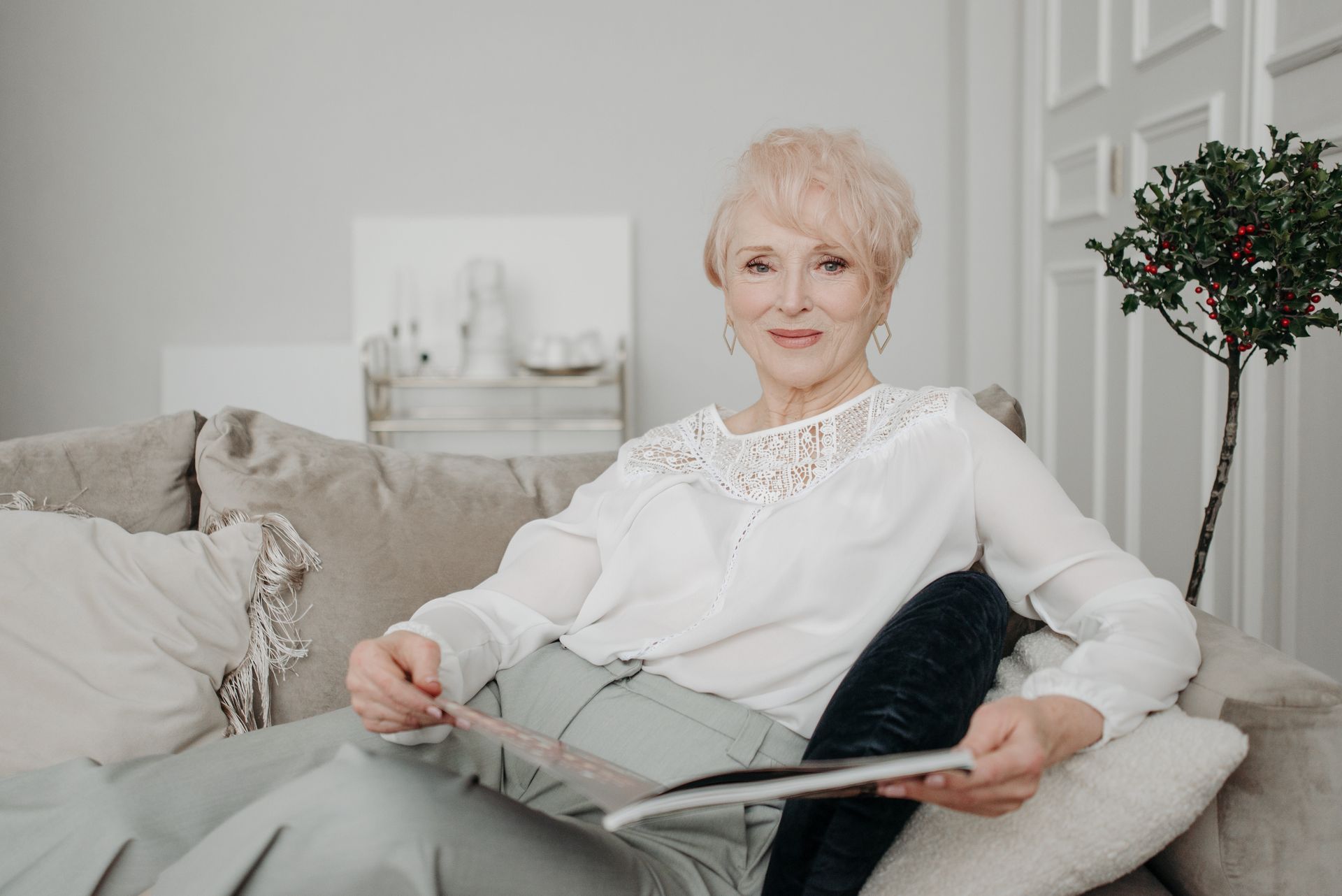 Elderly woman with white hair relaxing on a sofa in a sunlit living room