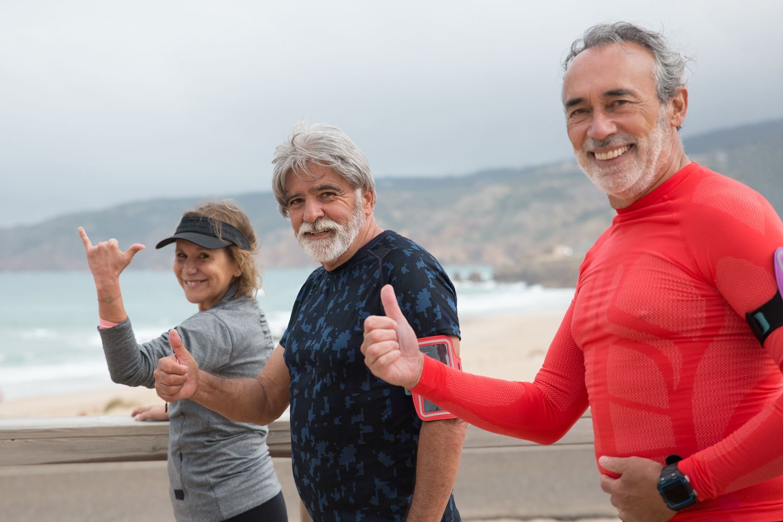 Senior friends walking together on a sunny beach in Portugal