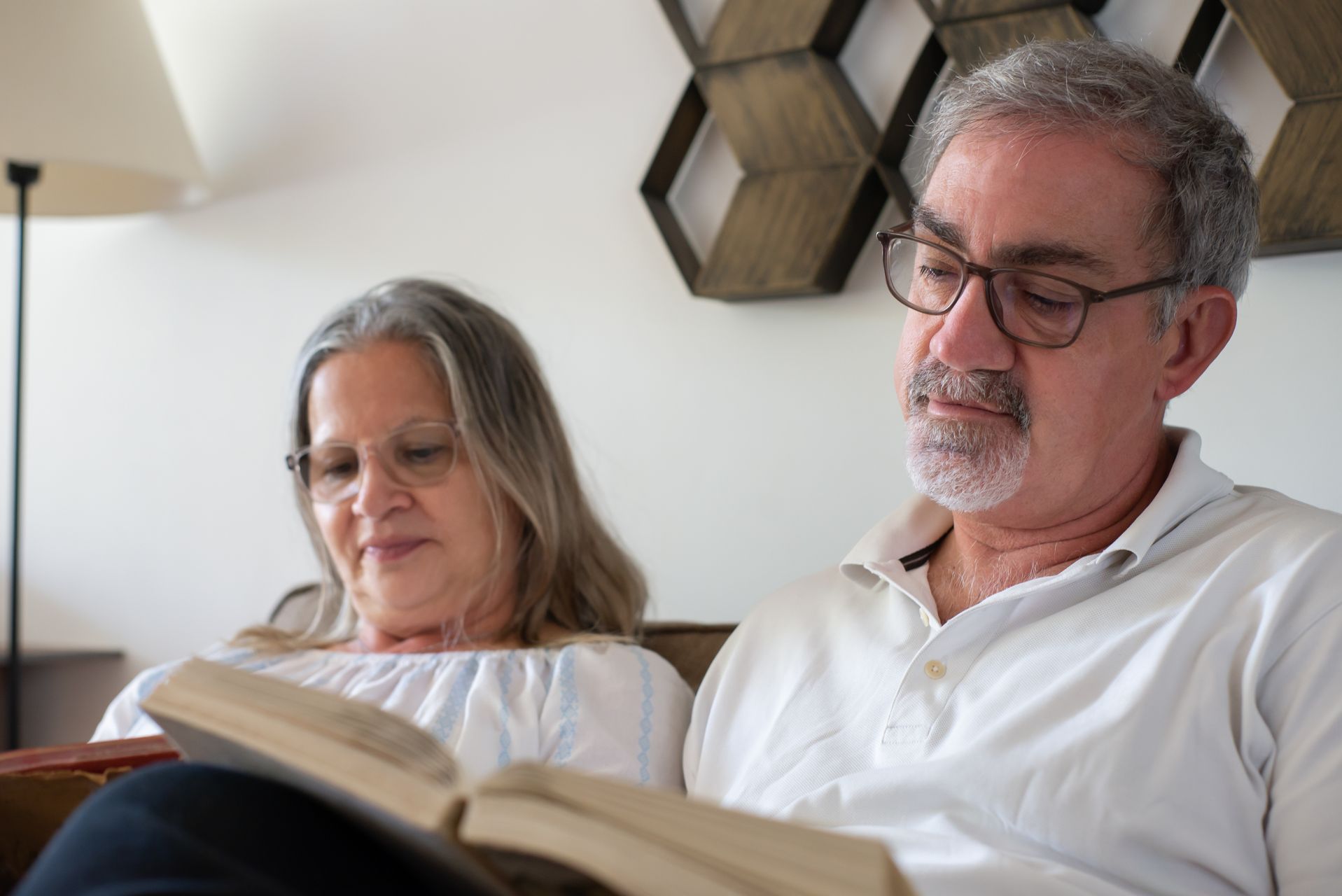 Mature couple reading together on a sofa in warm light at home