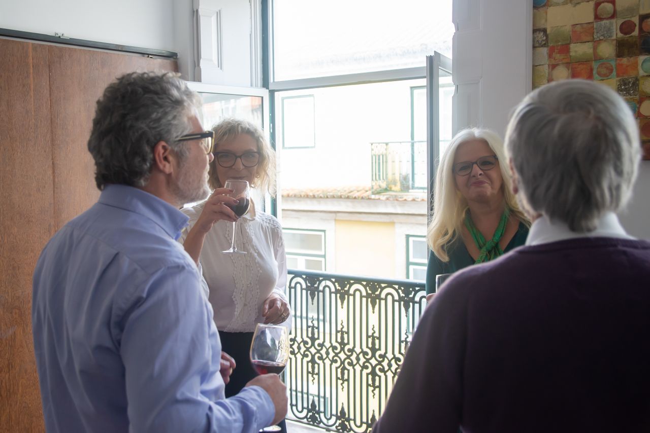 Older adults enjoying wine together at an indoor social gathering with warm evening light