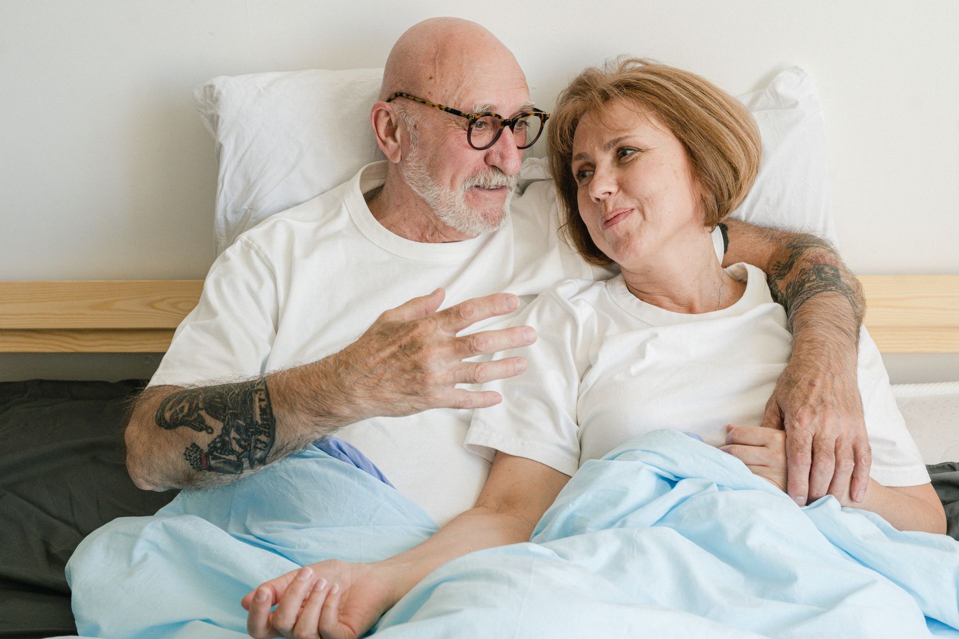 Older couple sharing a quiet affectionate moment in bed with soft natural light