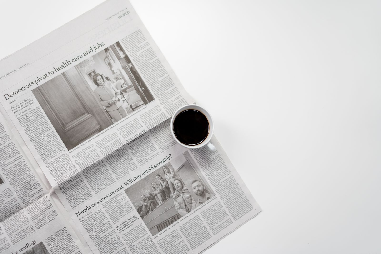 Two coffee cups on a sunlit kitchen table beside an open weekend newspaper, a quiet morning scene