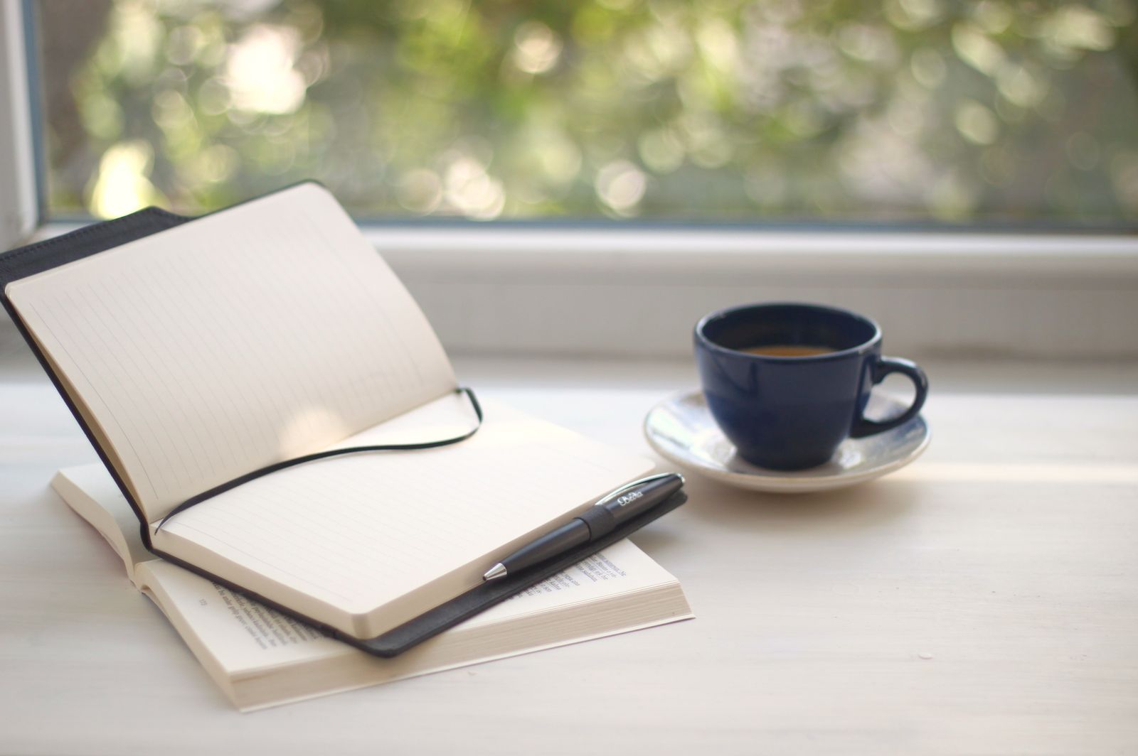 Open notebook and coffee beside a sunlit window on a calm desk
