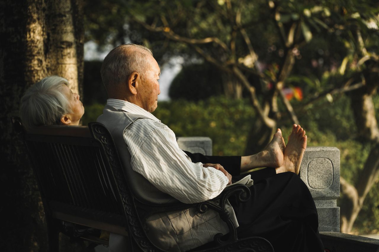 Elderly couple resting on a park bench in warm golden afternoon light